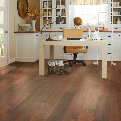 Home office with dark hardwood flooring, a beige desk, leather office chair, and built-in white cabinetry with a rolling library ladder.